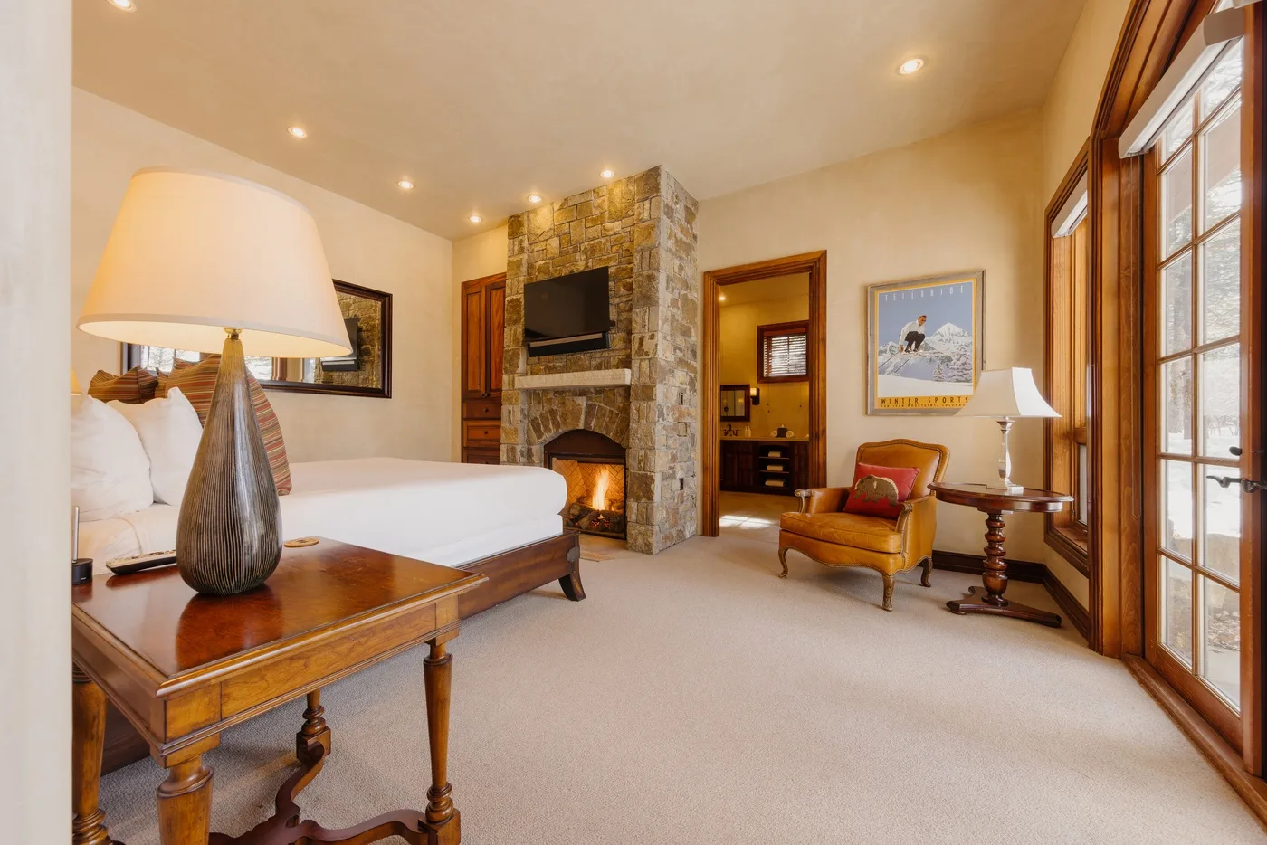 A bedroom with a stone fireplace, a bed, and a seating area.