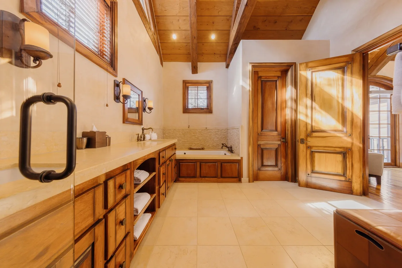 A spacious bathroom with wooden cabinetry, a bathtub, and an open wooden door.