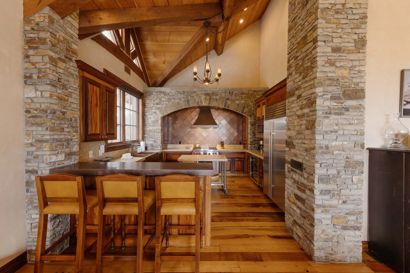 A rustic kitchen with a wooden dining table and stone cooking alcove.