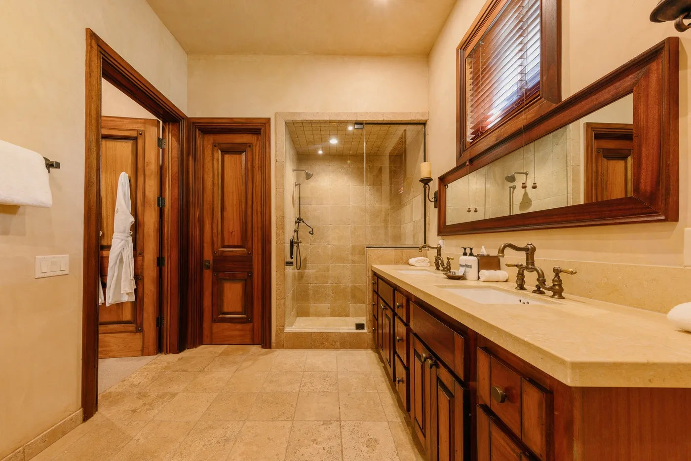 A spacious bathroom with a glass shower and a long vanity.