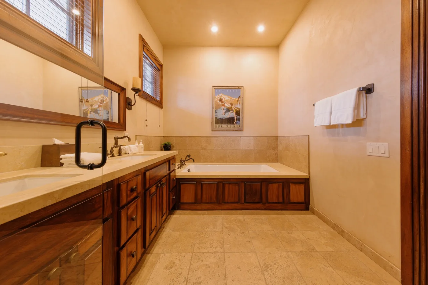 A spacious bathroom with a bathtub and a long wooden vanity.