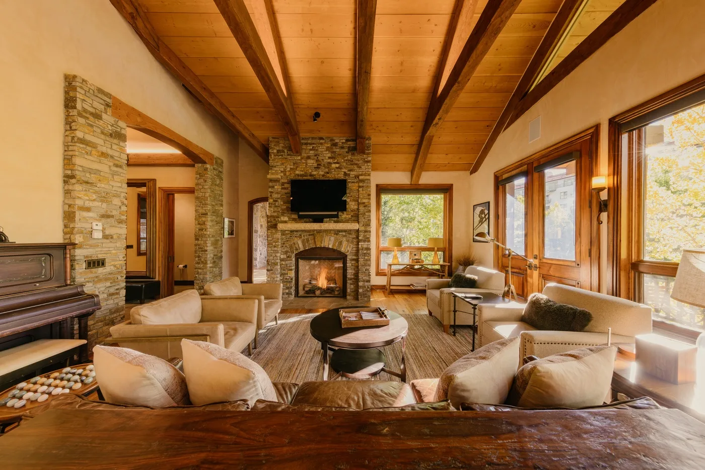 A living room with seating around a stone fireplace and large windows.