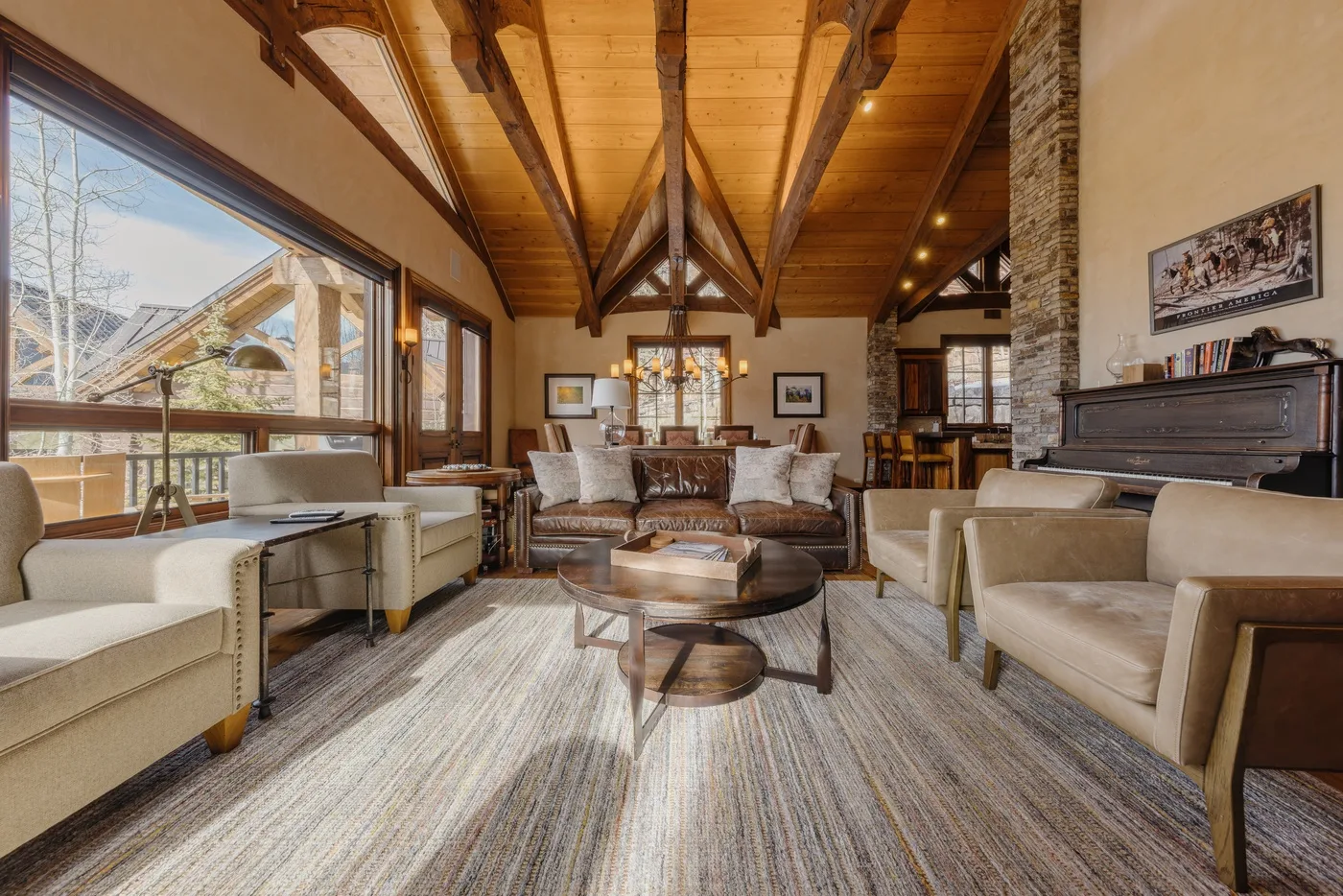 A living room with seating arranged around a coffee table beneath exposed wooden beams.