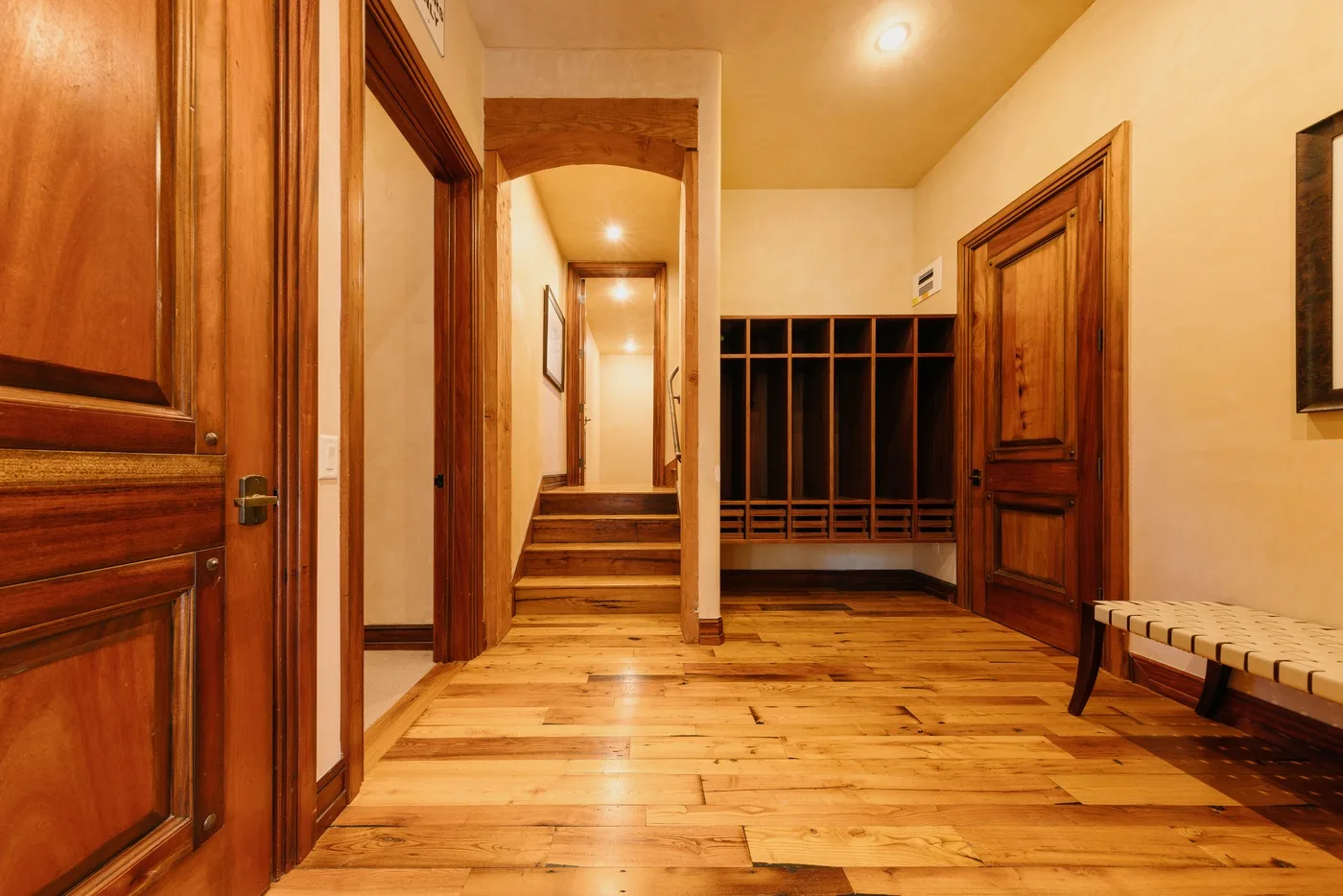 A wood-floored hallway with wooden doors and built-in shelving.
