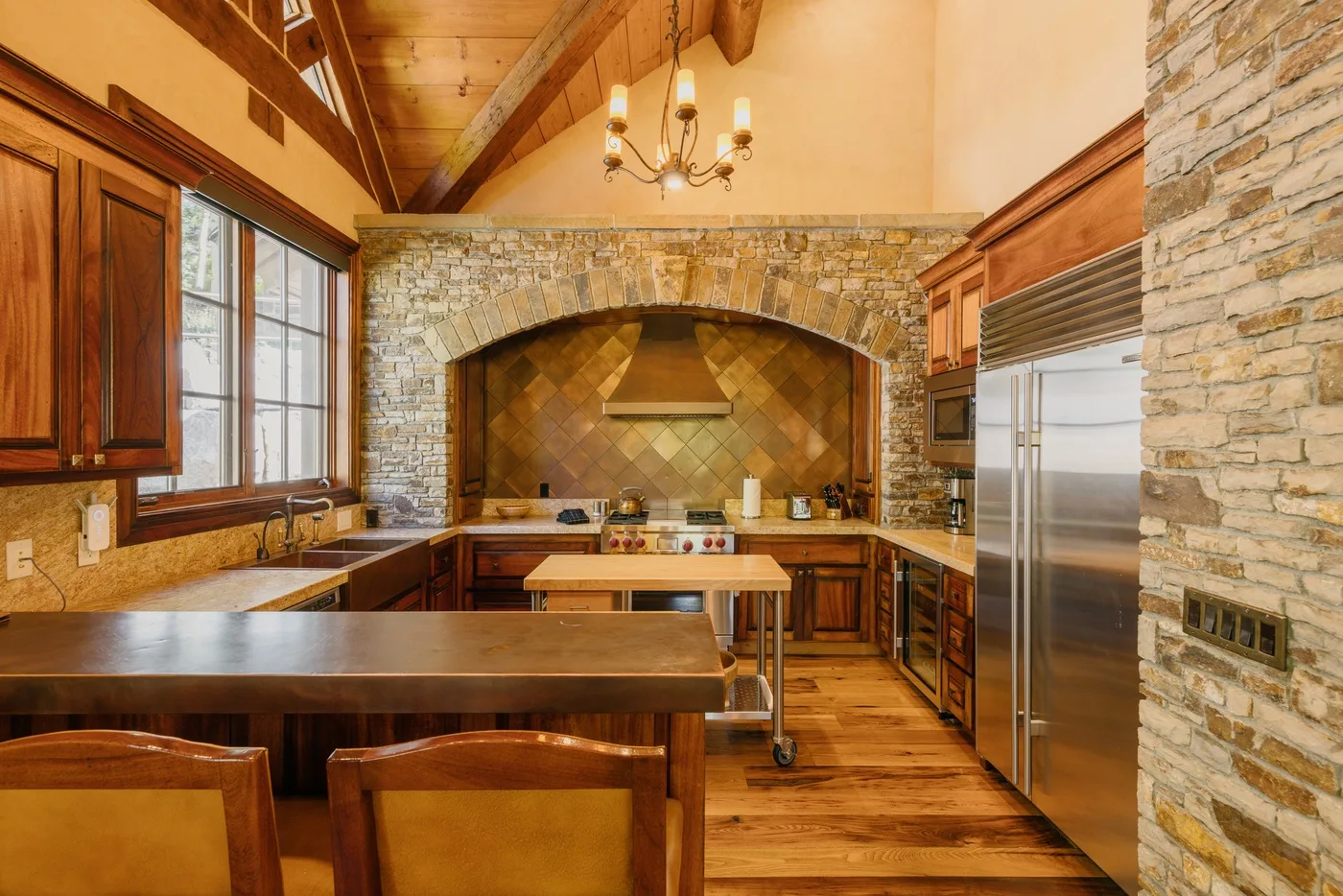 A wood-paneled kitchen with a stone arch over the cooking area and a large island.