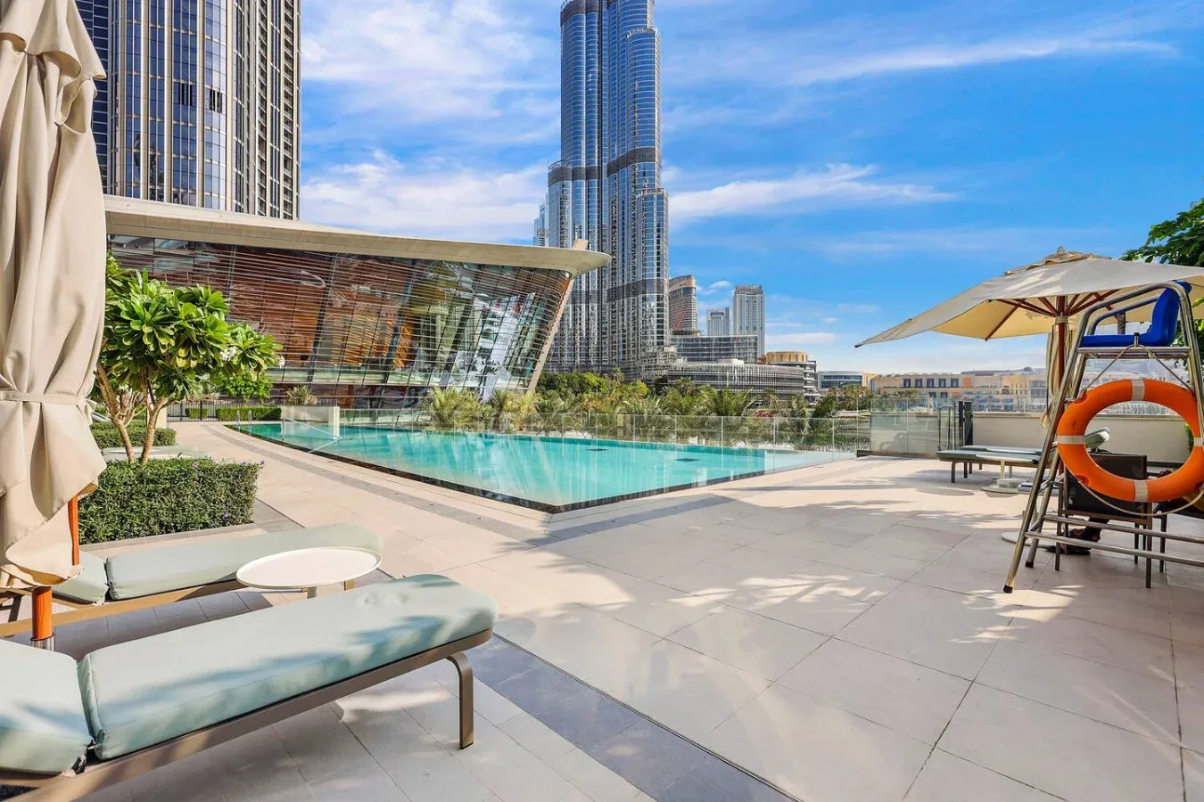 A rooftop pool terrace with lounge seating and surrounding city buildings.