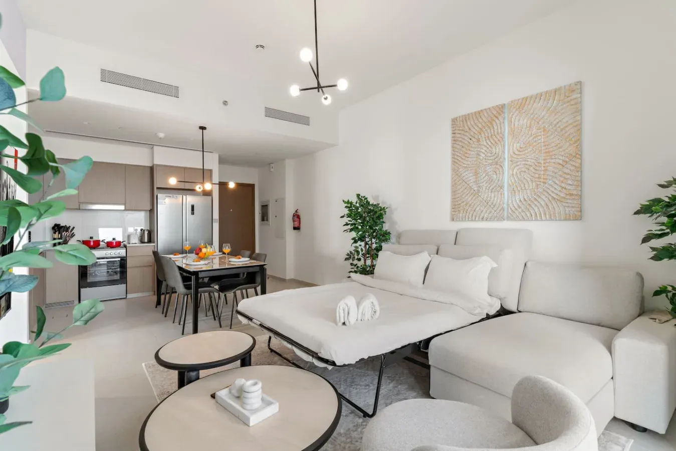 A bright open-plan living area with seating, a dining table, and a kitchen.