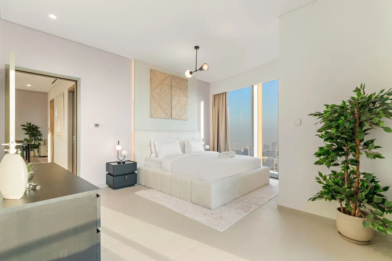 A bright bedroom with a large bed and floor-to-ceiling windows.