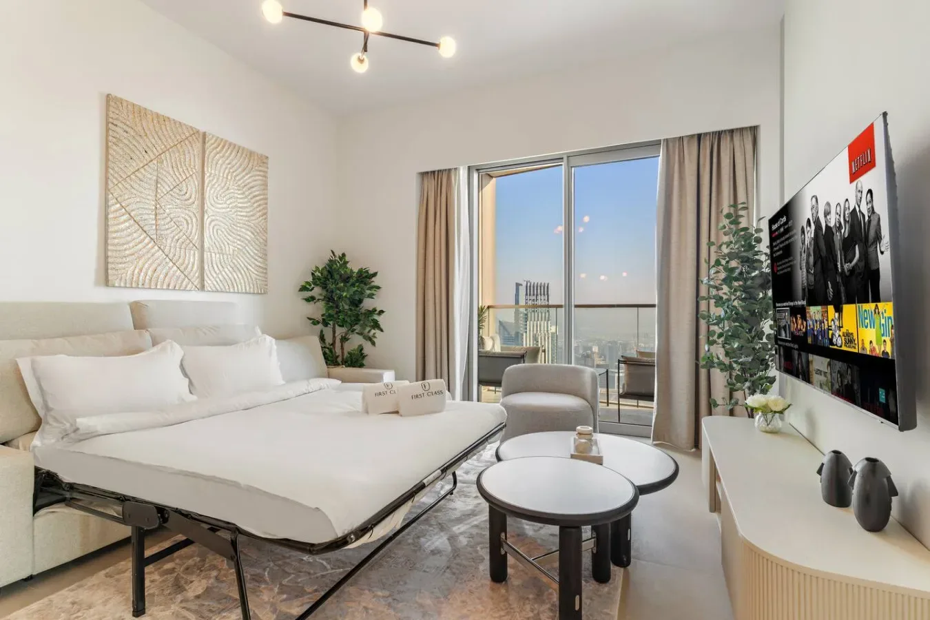 A bright living room with a bed, seating, and sliding glass doors to a balcony.