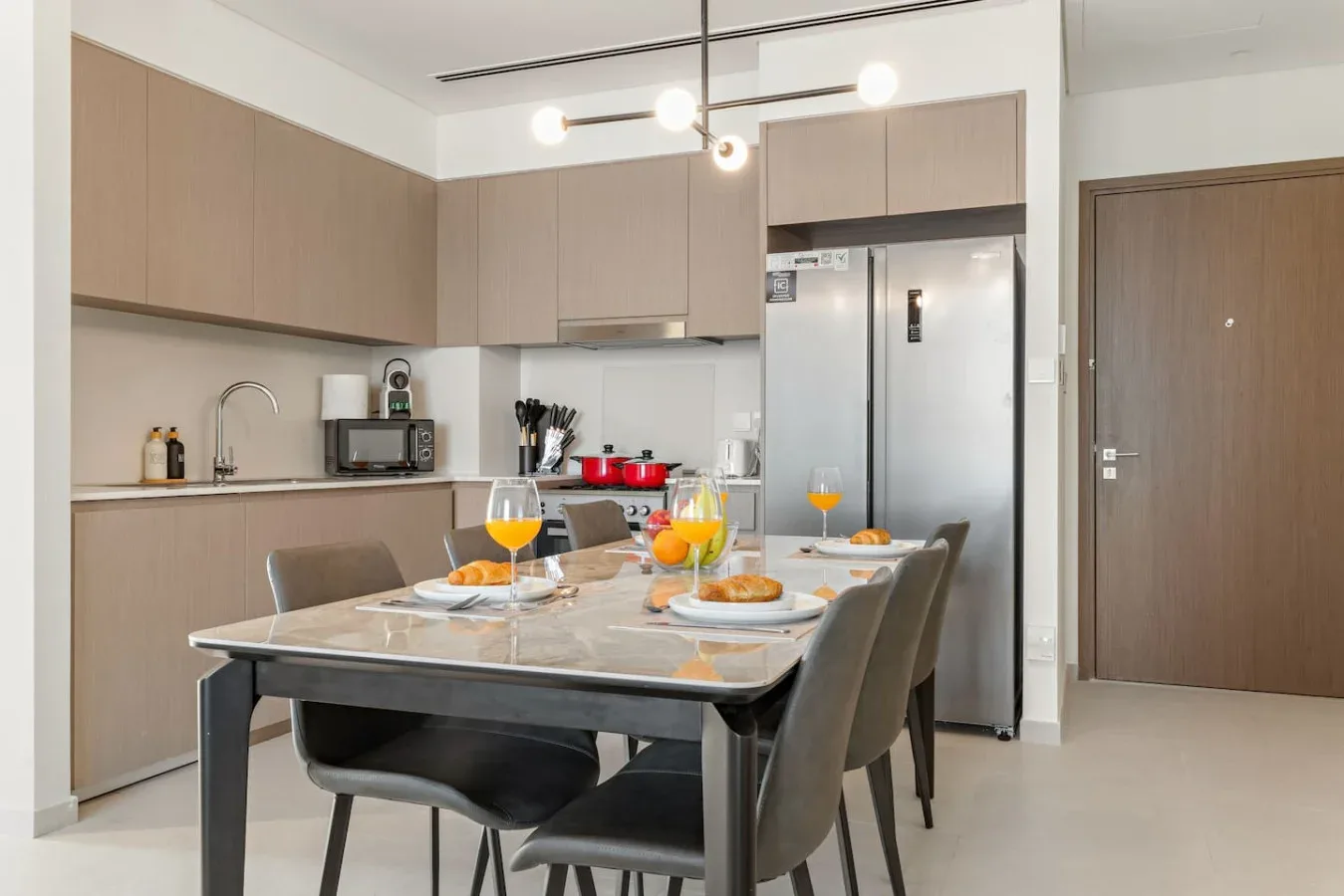 A modern kitchen and dining area with a set table and stainless steel refrigerator.