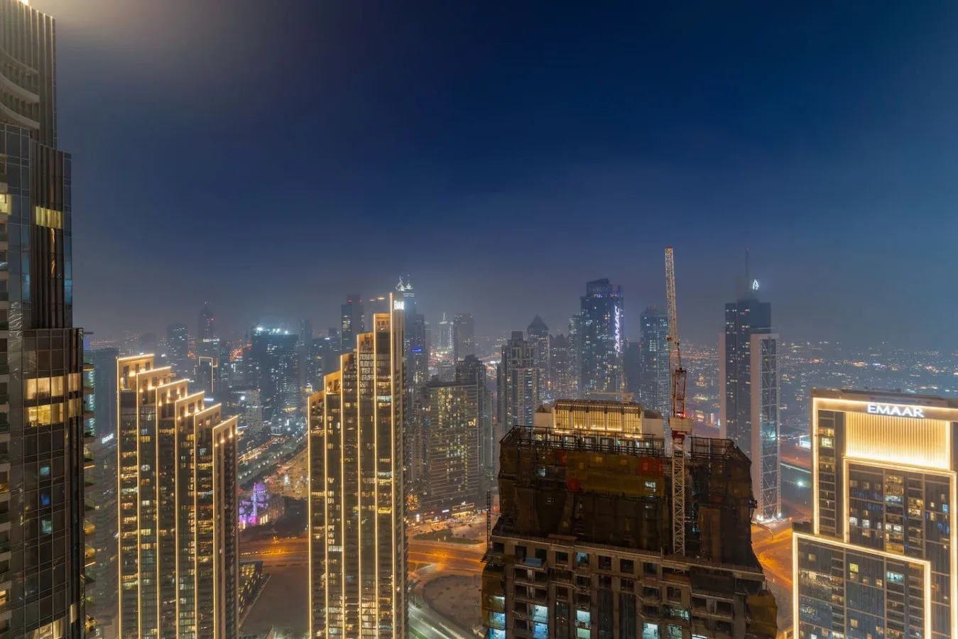 A nighttime city skyline with illuminated high-rise buildings.
