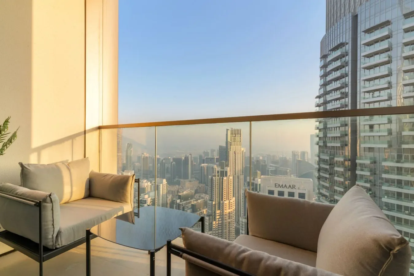 A high-rise balcony seating area overlooks a dense city skyline.