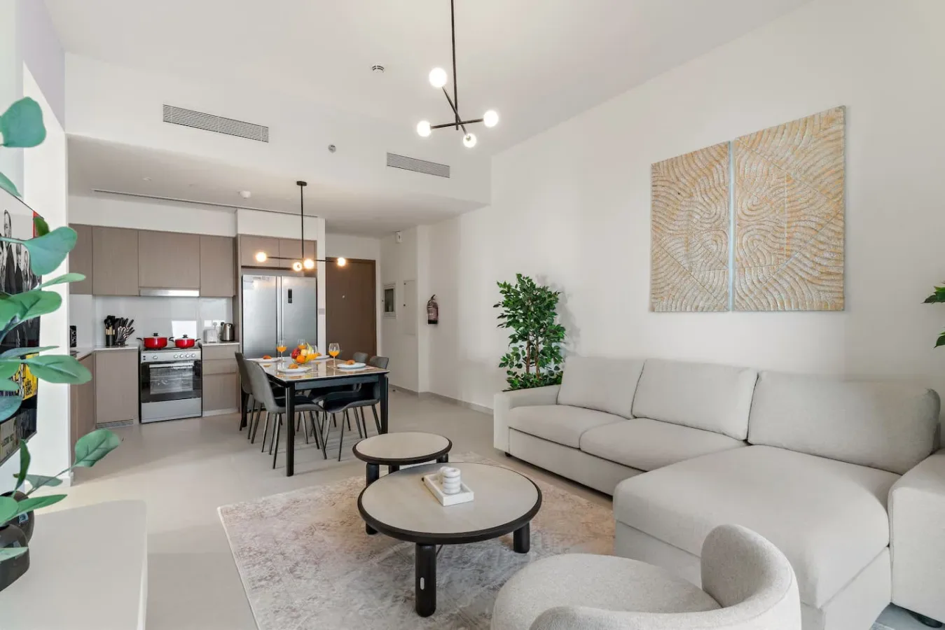 An open-plan living and dining area with a pale sectional and round coffee tables.
