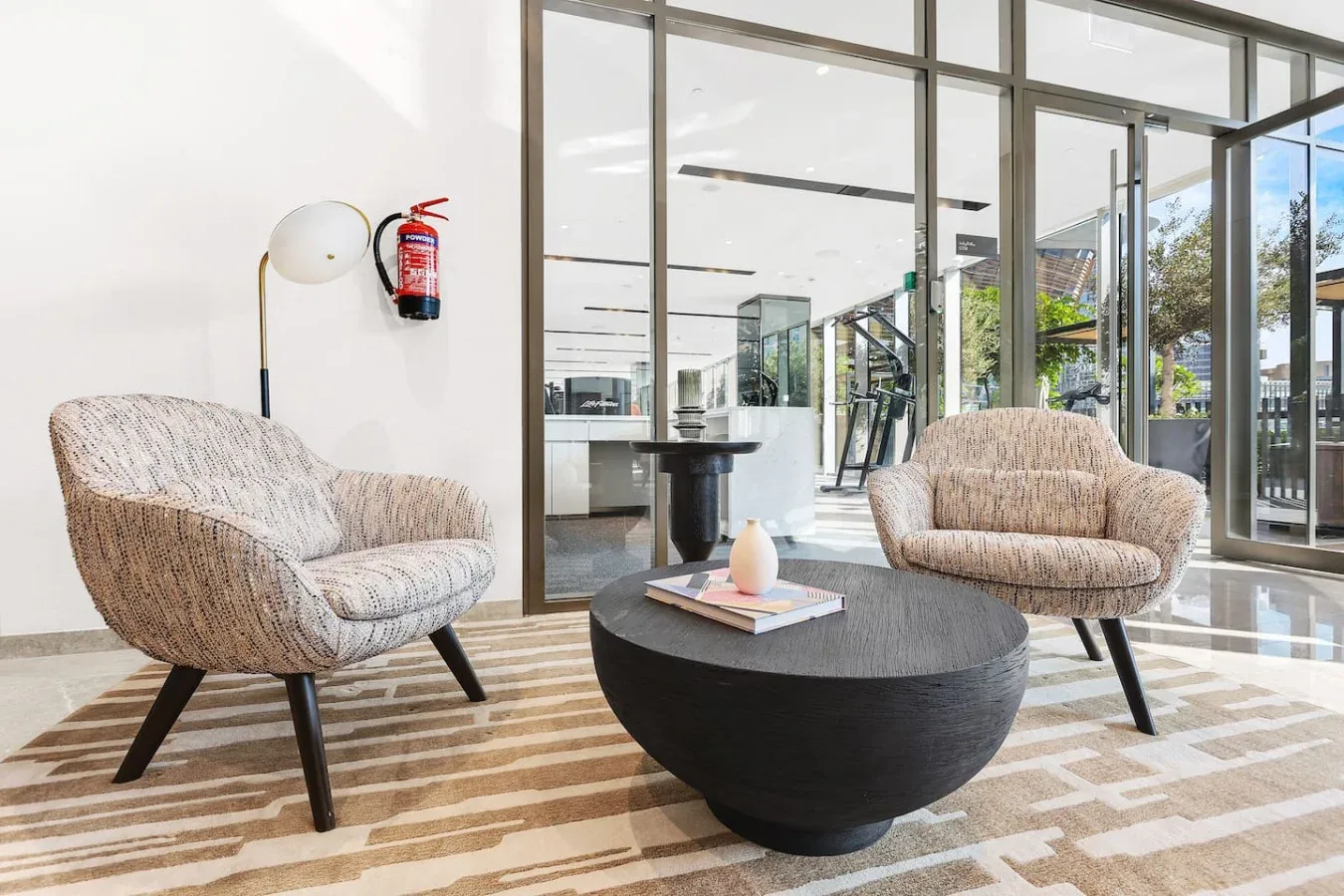 A bright lobby seating area with two upholstered seats around a low round table.