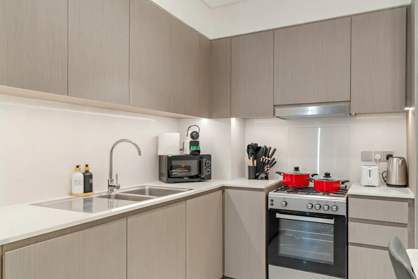 A modern kitchen with pale cabinets, a countertop, and a stove.