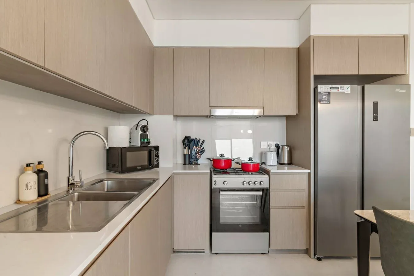 A modern kitchen with light cabinetry, a stove, and a refrigerator.