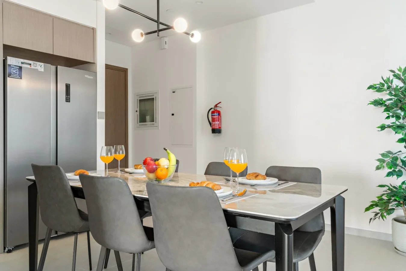 A dining area with a set table and fruit beside the kitchen.