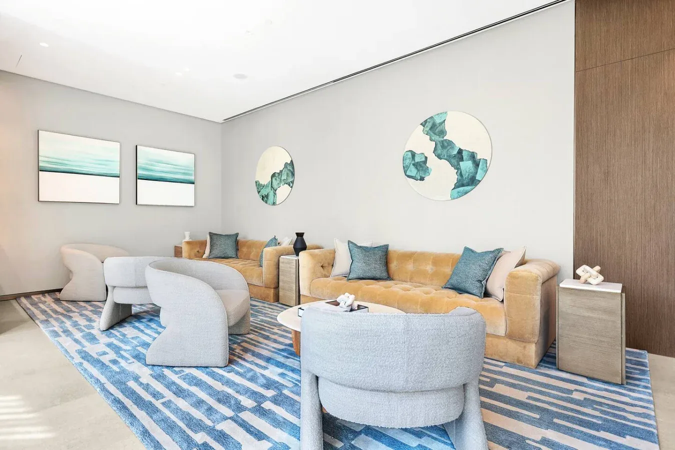A bright living room with seating arranged around a blue patterned rug.