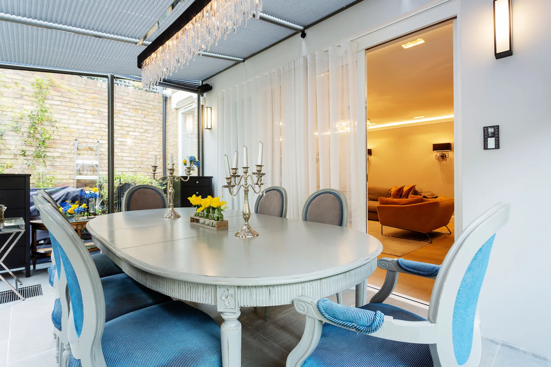 A bright dining area with a large table and chairs beside a glass wall.