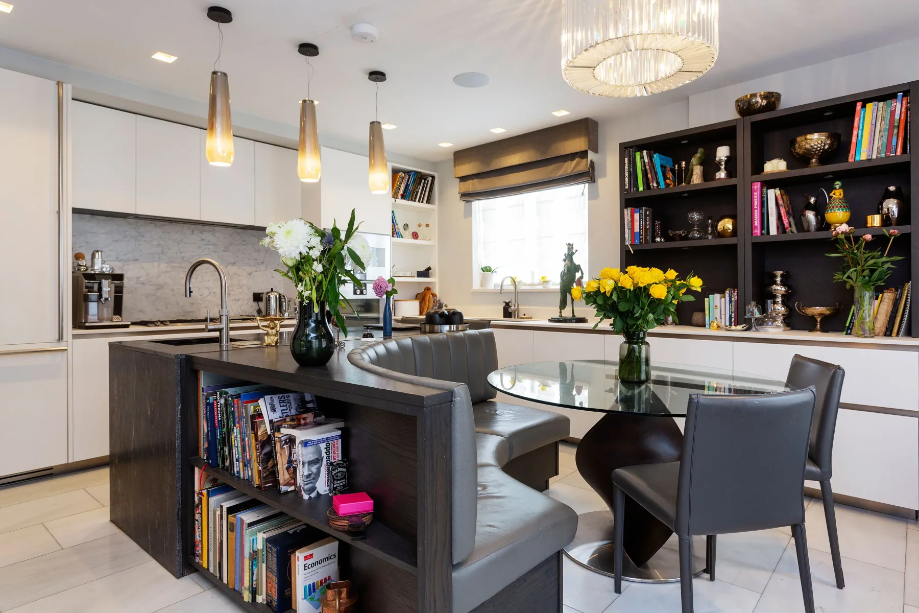 Una cocina y comedor luminosos con una mesa de vidrio y estanterías integradas.