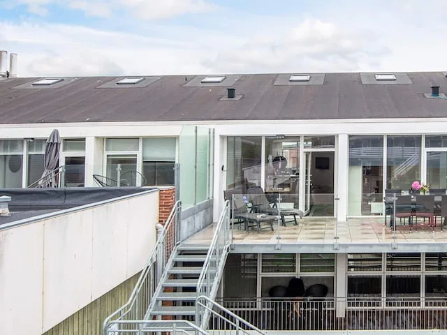 A modern building with an outdoor terrace, patio seating, and exterior stairs.
