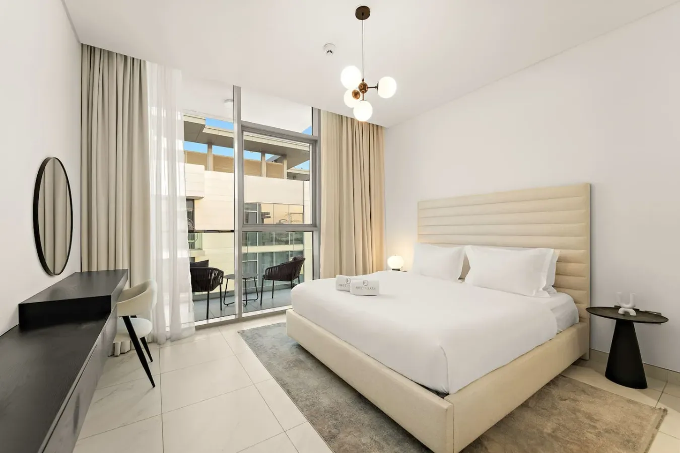 Un dormitorio luminoso cuenta con una cama bien tendida junto a ventanales de piso a techo.