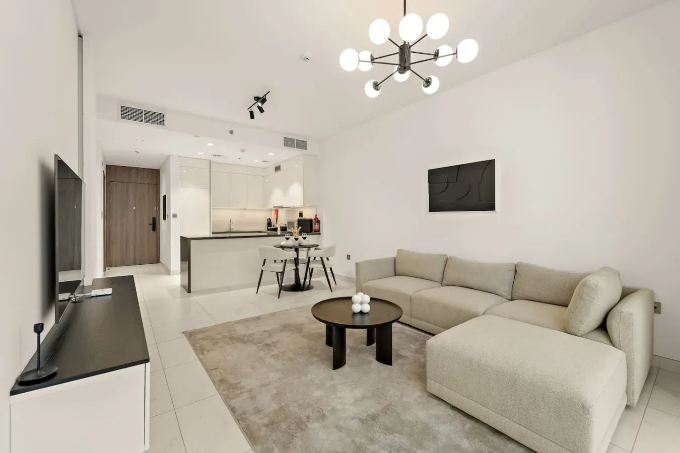 A bright living room with a sectional seating area beside an open kitchen.
