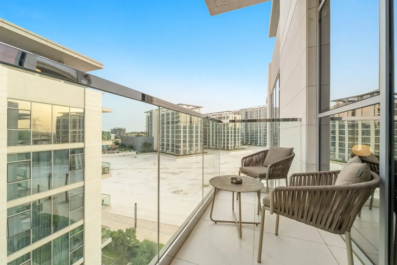 A balcony seating area overlooks nearby modern buildings.