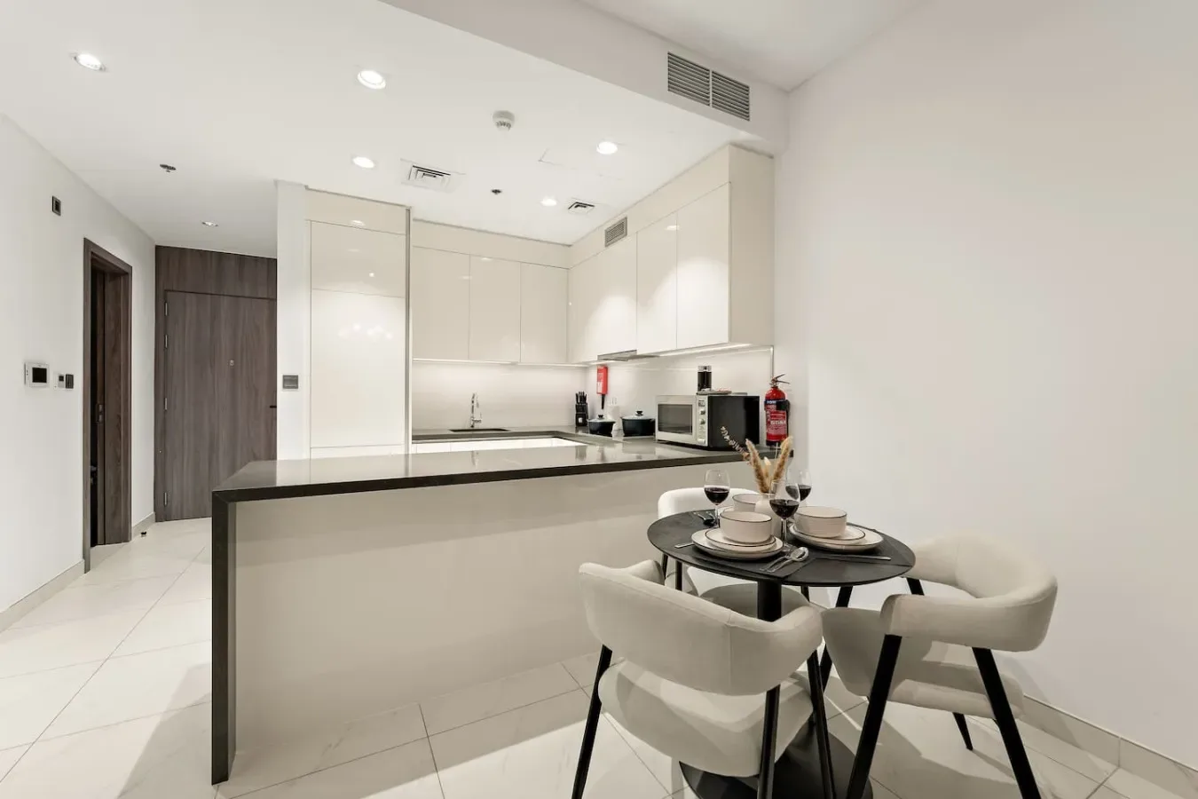 Una cocina y comedor luminosos con gabinetes blancos y una mesa.