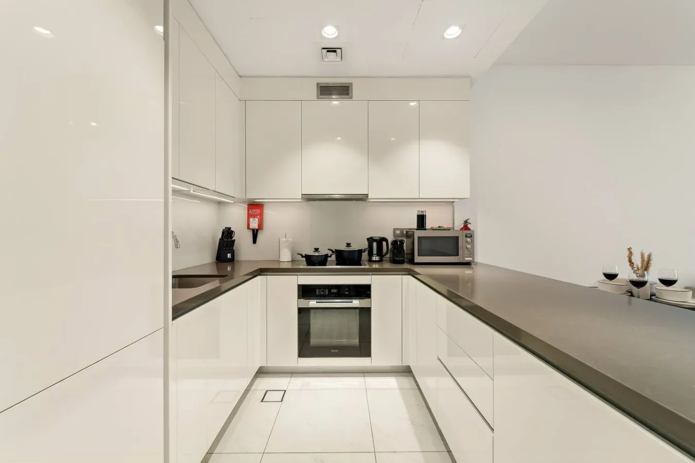 Una cocina moderna y luminosa con gabinetes blancos y una encimera oscura.