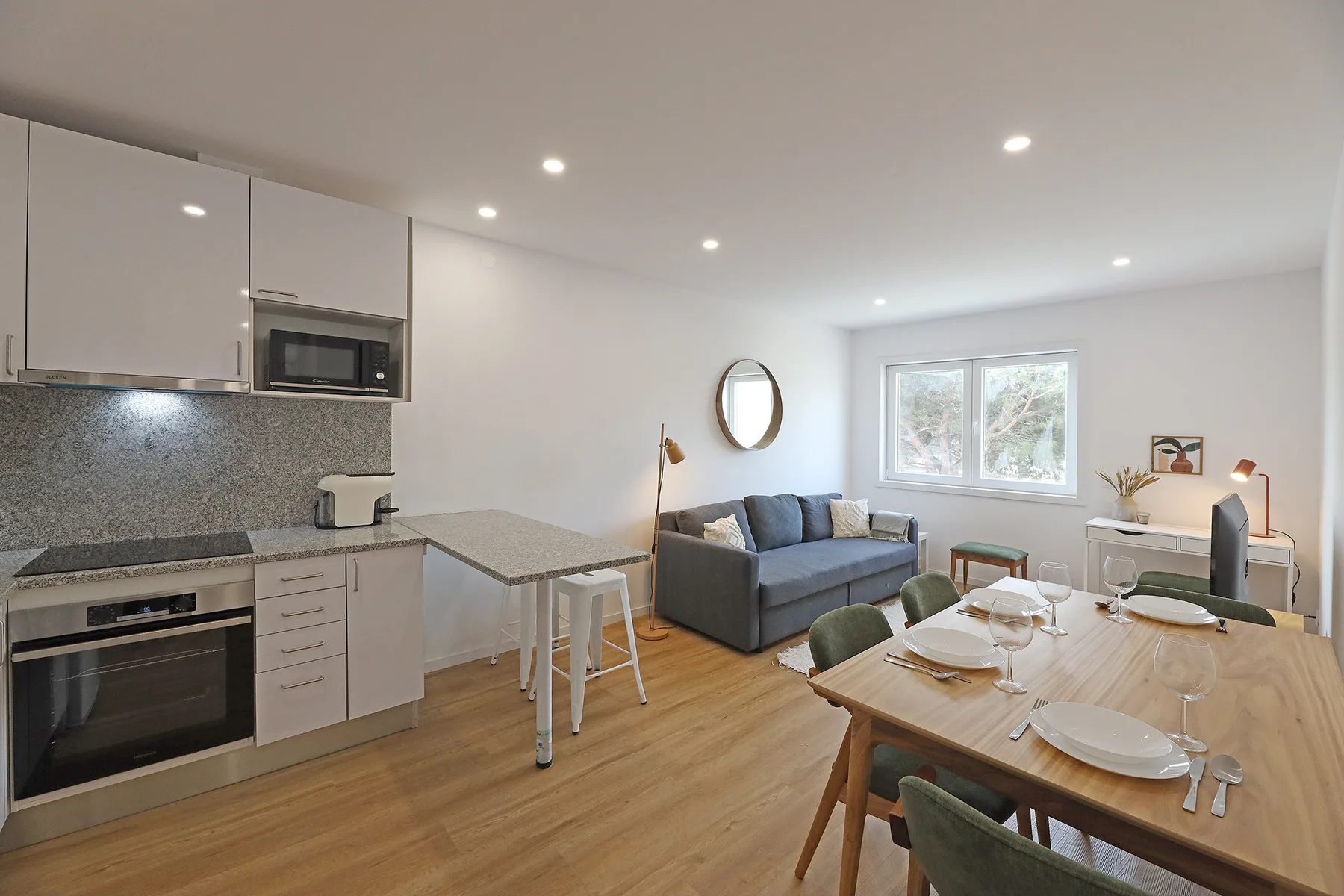 An open-plan kitchen and dining area with a living space beside the window.