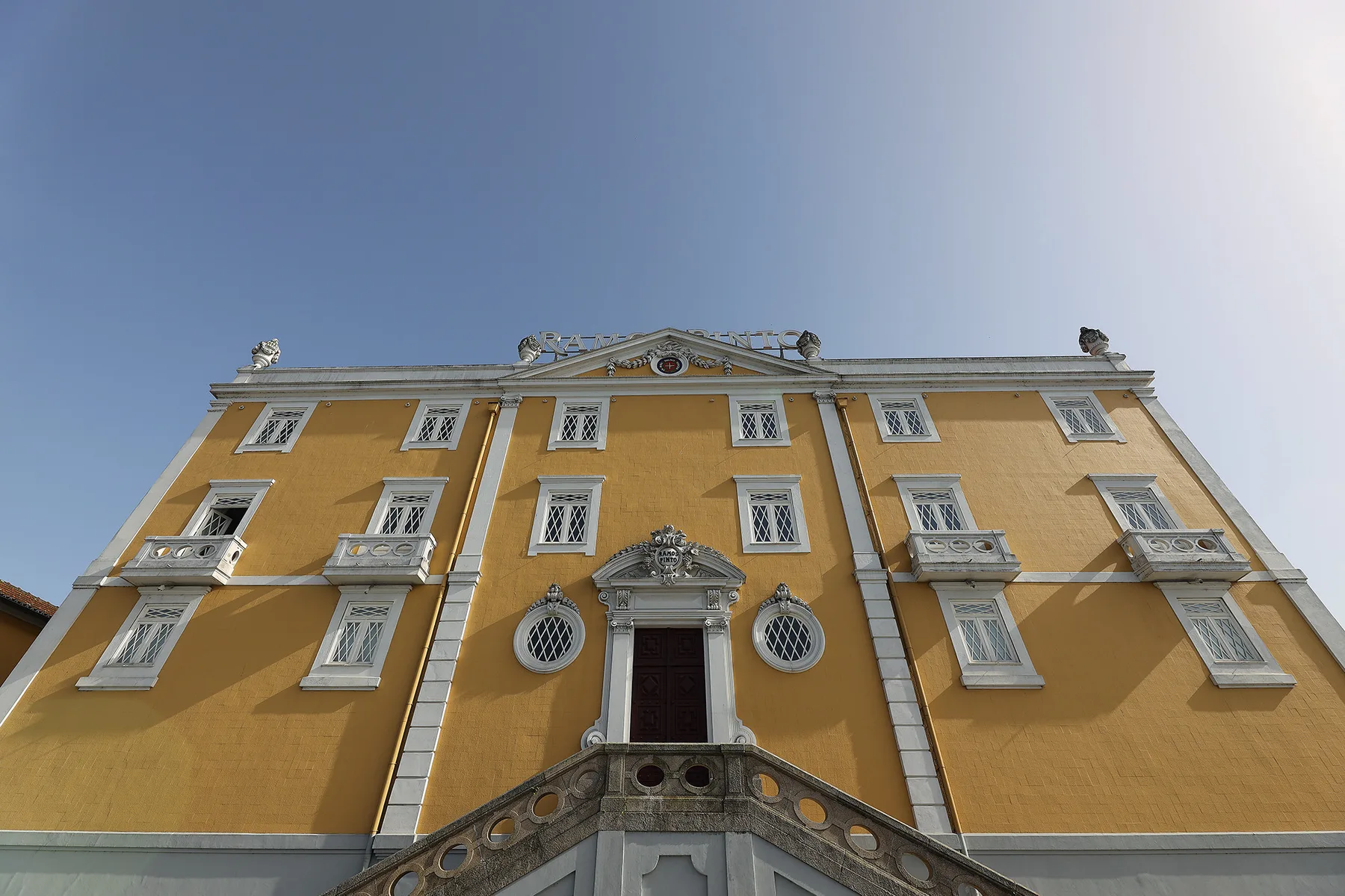 An ornate yellow building facade with white-trimmed windows beneath a clear sky.