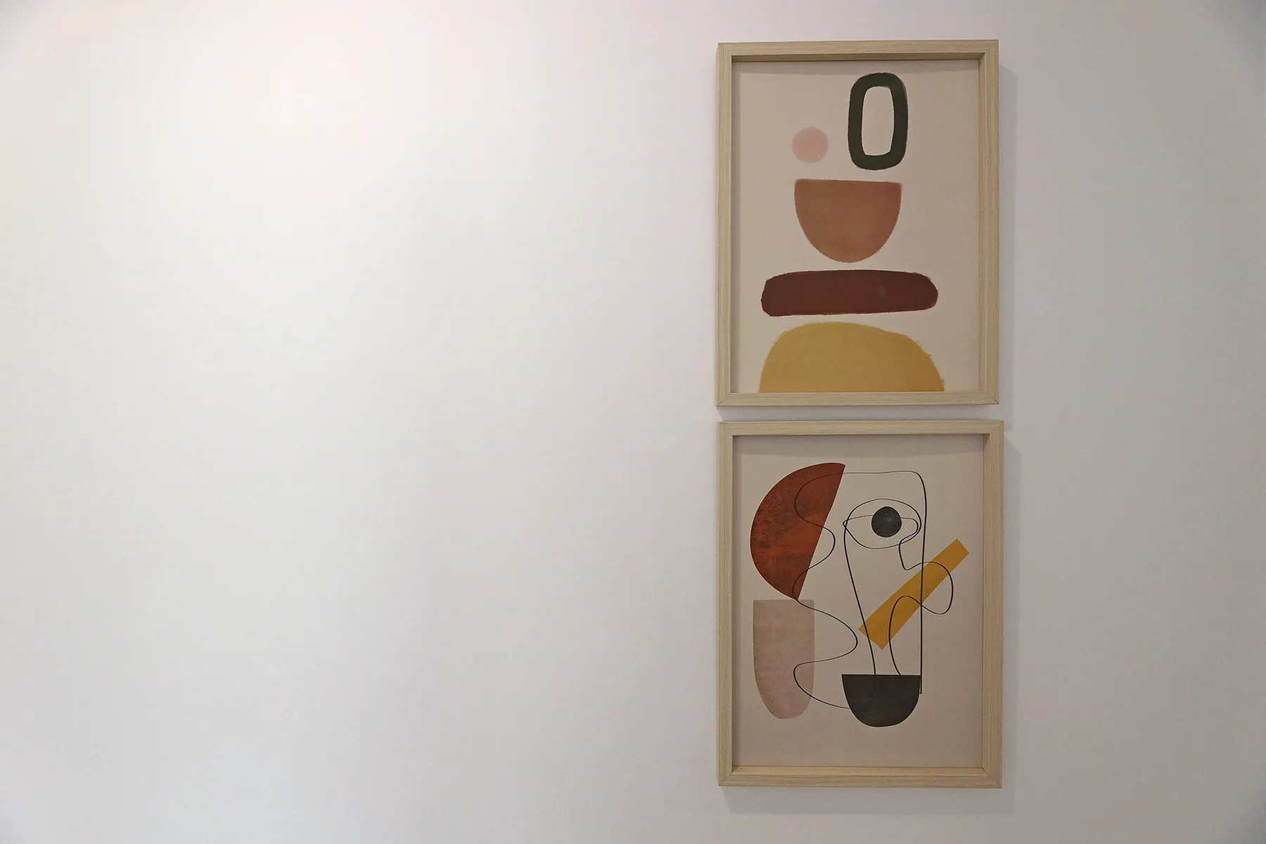 A plain wall displays two framed abstract artworks.