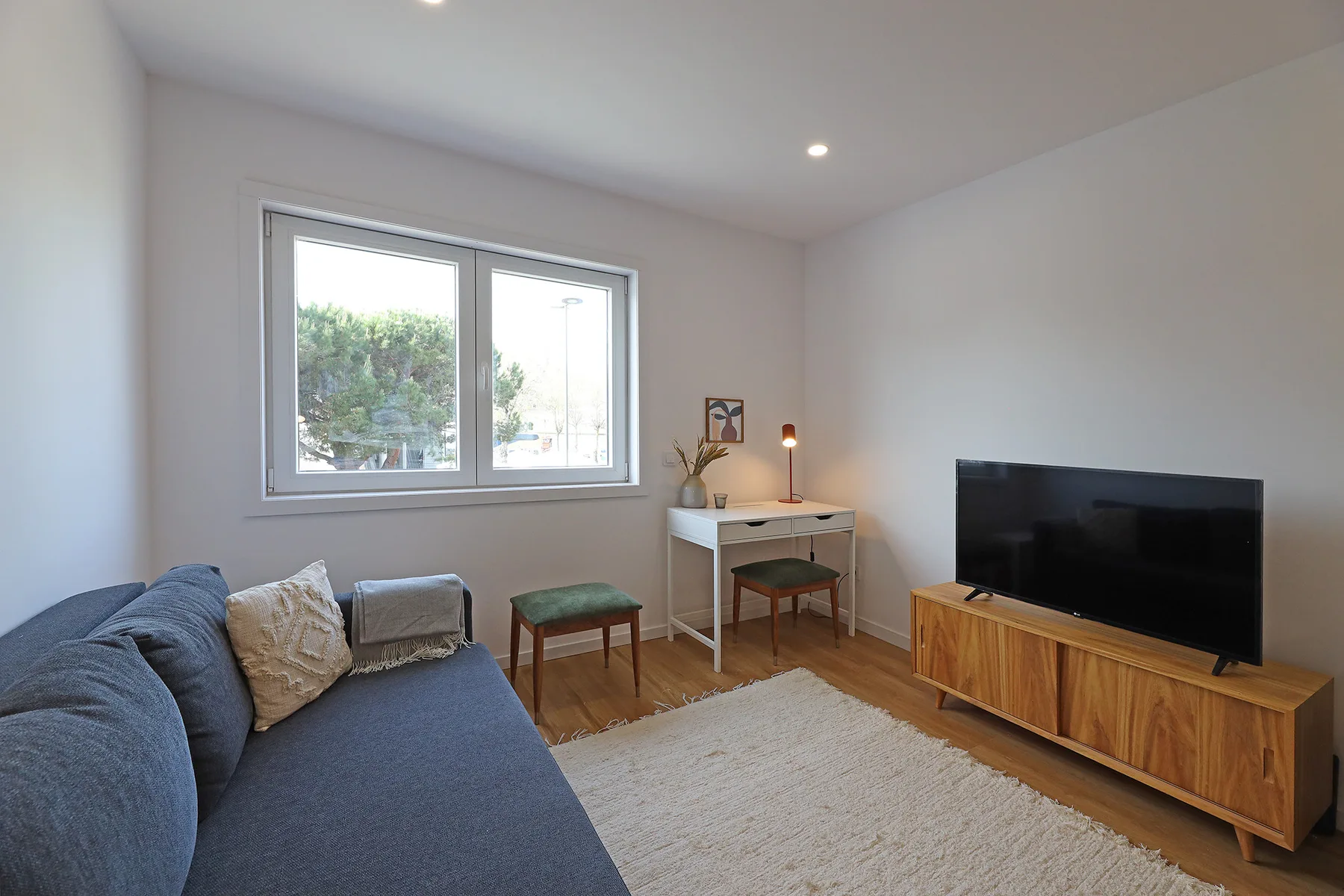 A living room with seating, a television, and a window.