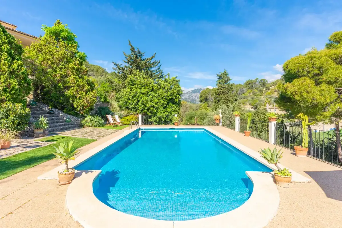A swimming pool sits among green trees and landscaped grounds.