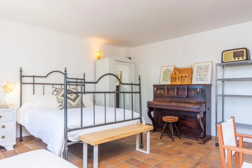 A bedroom with a metal bed, a piano, and a wooden bench.
