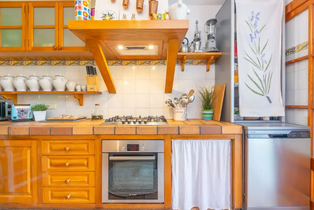 A warm-toned kitchen with a cooktop, oven, and wooden cabinets.