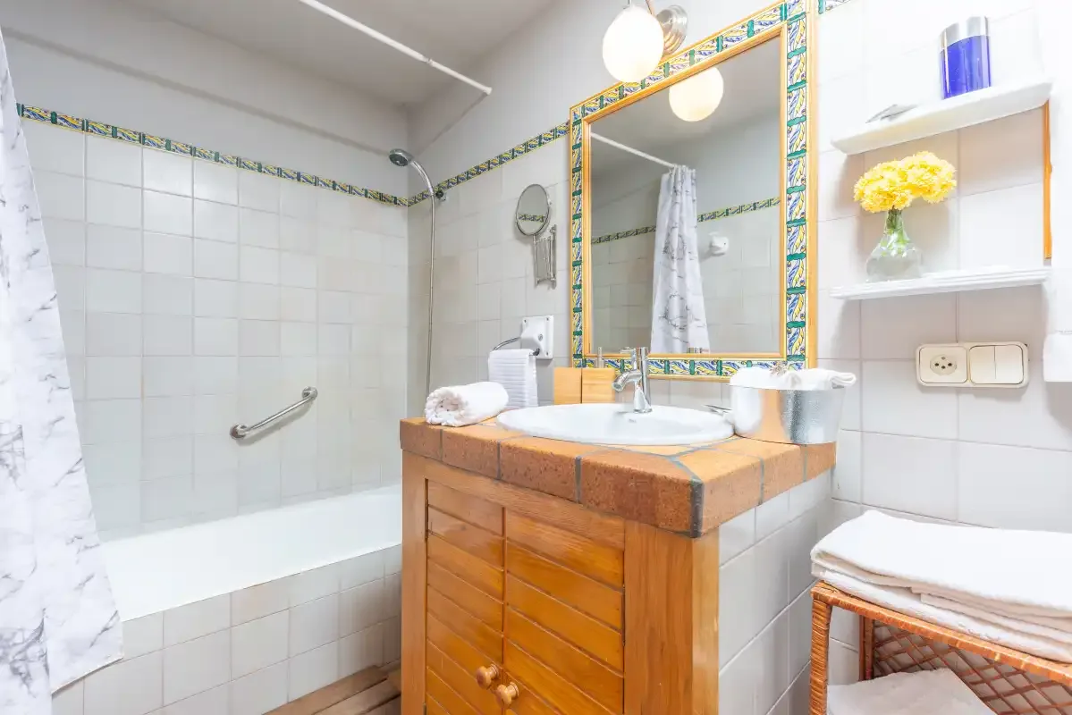 A bathroom with a tiled shower, sink, and wooden vanity.