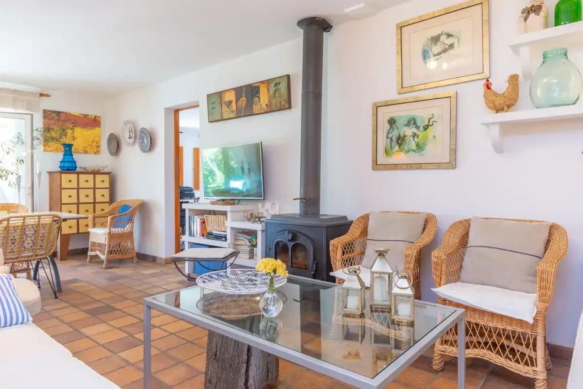 A living room with wicker seating, a glass coffee table, and a freestanding stove.