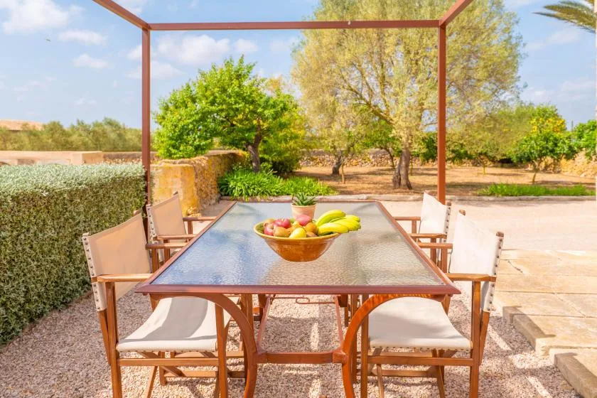 Comedor al aire libre con una mesa y sillas junto a un jardín.