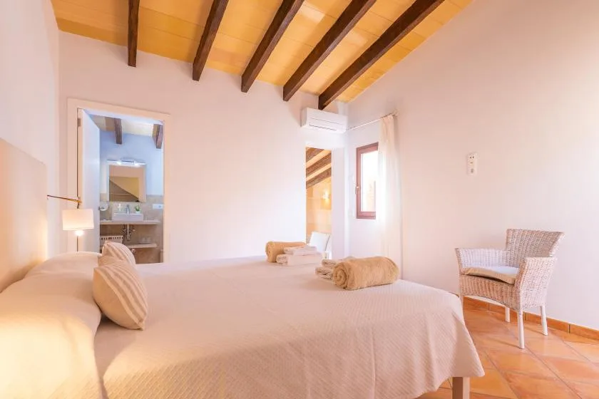 Un dormitorio con una cama grande y una silla tejida junto a la ventana.