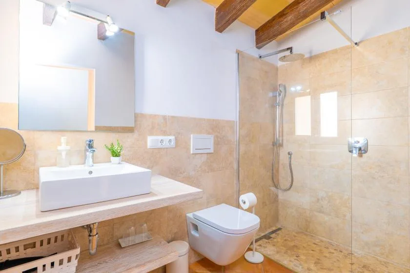 Un baño con lavabo, espejo y ducha con mampara de vidrio.