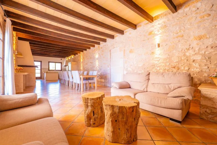 Una sala rústica con comedor, asientos, mesas de troncos y vigas expuestas.