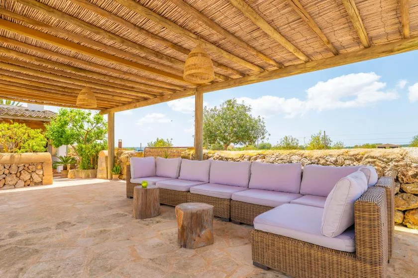 Una zona exterior cubierta con asientos acolchados y vistas al paisaje.
