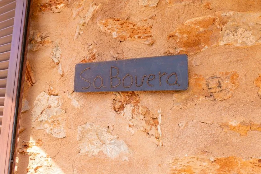 Una pared de piedra muestra una pequeña placa junto a una persiana.