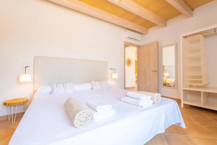 Un dormitorio luminoso con una cama grande y vigas de madera expuestas en el techo.