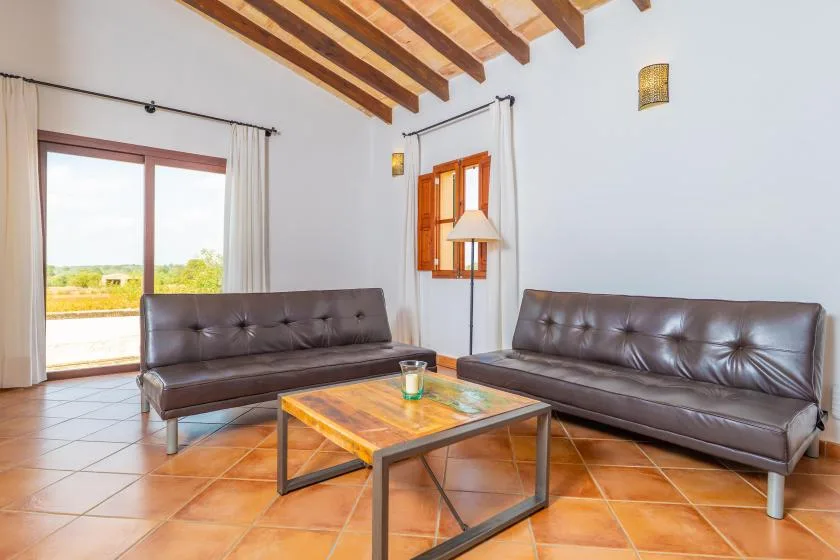 Una sala luminosa con dos sofás oscuros y una mesa de centro baja.