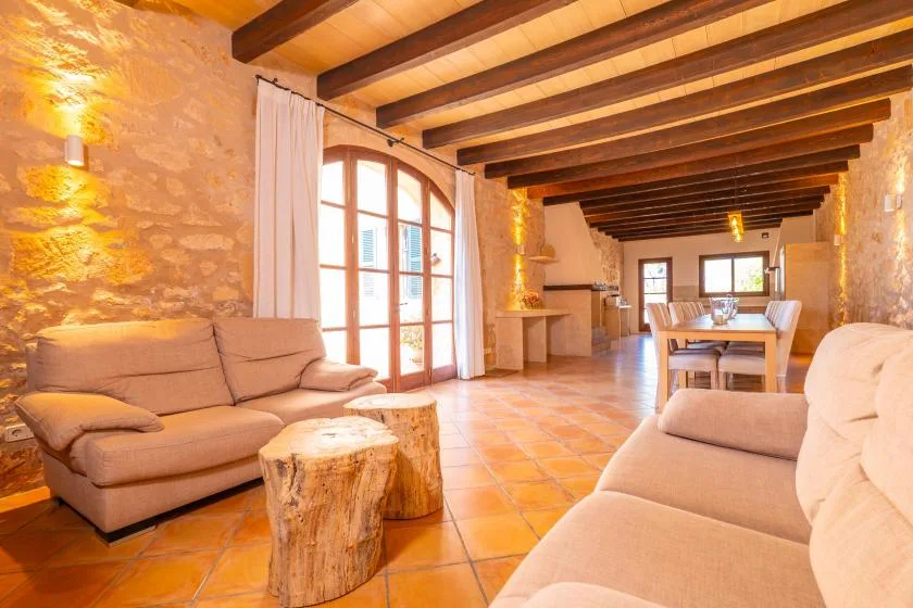 Una sala rústica con comedor, asientos, una mesa de madera y vigas expuestas en el techo.