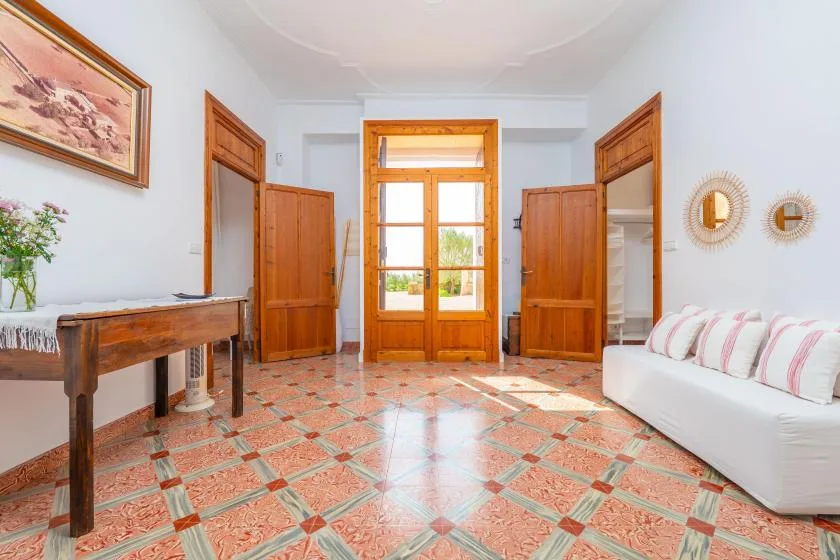 Una sala luminosa con puertas de madera y un sofá blanco.