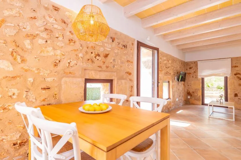 Un comedor rústico con una mesa de madera y asientos blancos.